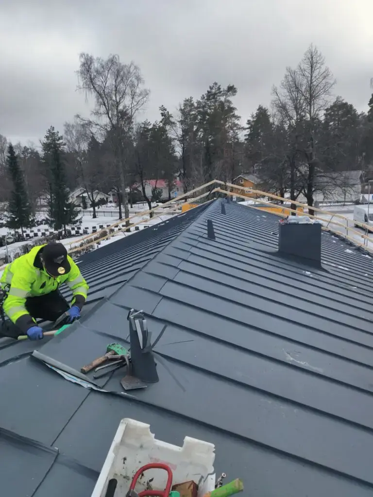 peltikaton korjaus talvisäässä, ammattilainen paikkaa peltikatoa lumisessa säässä, omakotitalo Uusimaa
